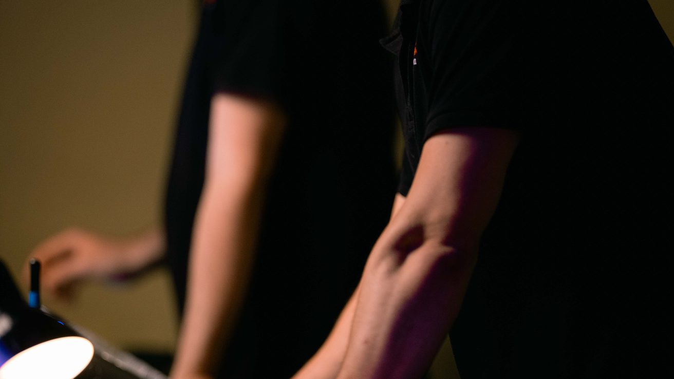 Two technicians dressed in black working on the sound desk in the Music Room