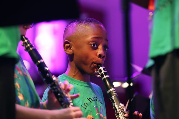 Boy in green t-shirt playing clarinet on stage