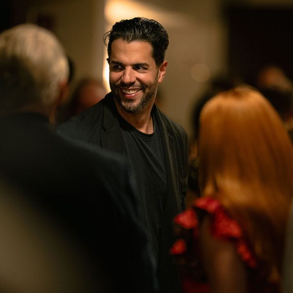 Domingo Hindoyan, dark hair, wearing all black and smiling at two people who have their back turned