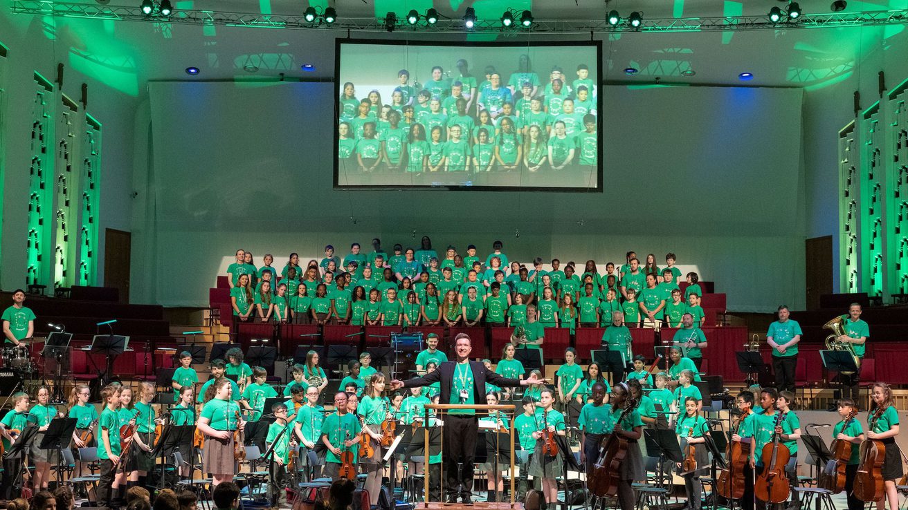 Liverpool Philharmonic Hall stage full of young In Harmony musicians all stood up and facing the audience
