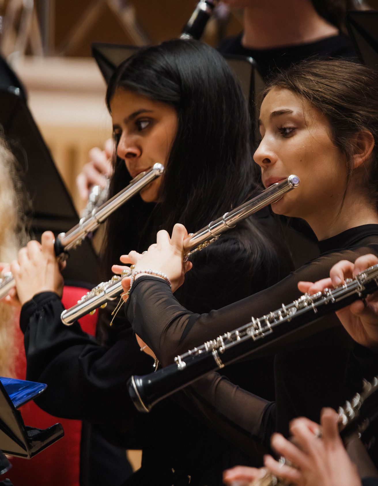 Three girls dressed in black playing the violin on stage