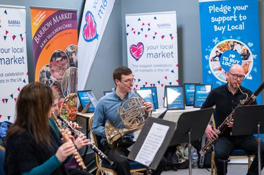 Four musicians from the Royal Liverpool Philharmonic Orchestra playing the flute, oboe, bassoon and French horn perform in a pop-up concert at Barrow Market