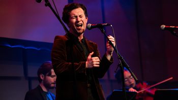 MT Jones in a velvet jacket singing on stage in the Music Room