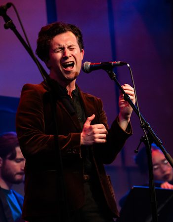 MT Jones in a velvet jacket singing on stage in the Music Room