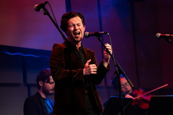 MT Jones in a velvet jacket singing on stage in the Music Room
