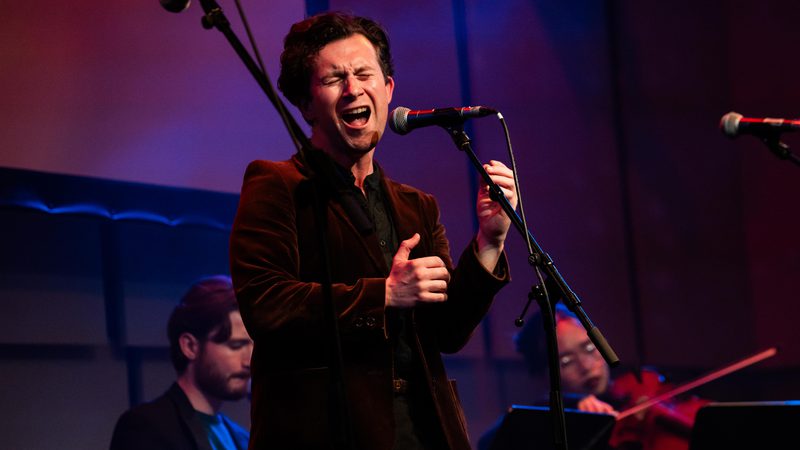 MT Jones in a velvet jacket singing on stage in the Music Room