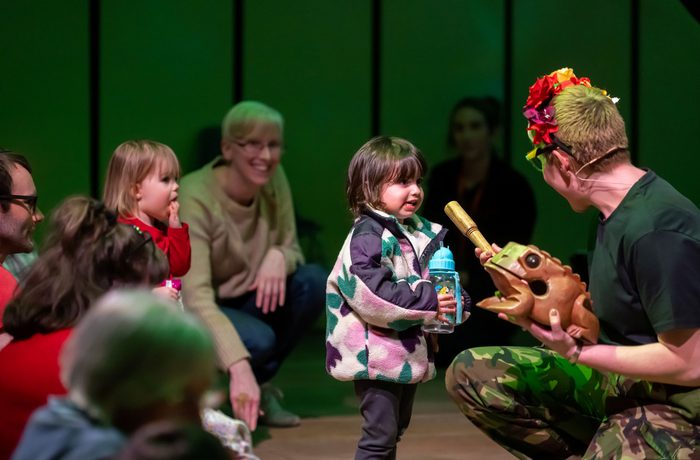 Under 5s concert presenter Claire Henry showing a frog-shaped percussion instrument to a toddler