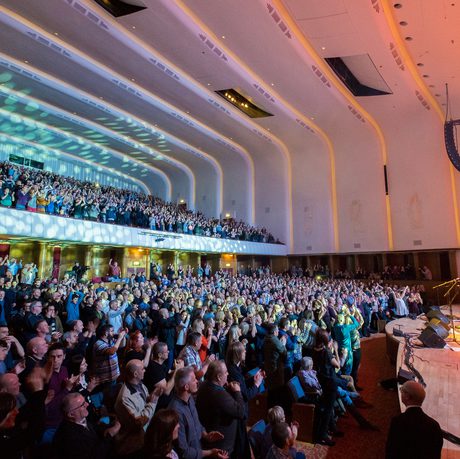 Audience on their feet with lights on the back wall of Liverpool Philharmonic Hall