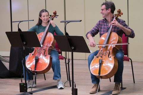 Two musicians laughing and playing the cello