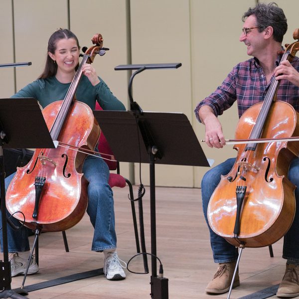 Two musicians laughing and playing the cello