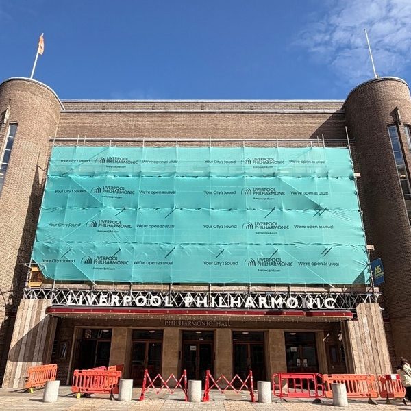 Liverpool Philharmonic Hall with scaffolding at the front, all wrapped in a teal cover