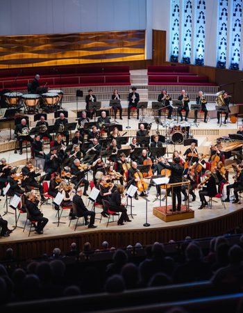 A photo of the Royal Liverpool Philharmonic Orchestra performing on stage, taken from above in the Grand Circle
