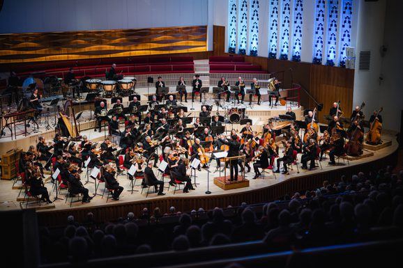 A photo of the Royal Liverpool Philharmonic Orchestra performing on stage, taken from above in the Grand Circle