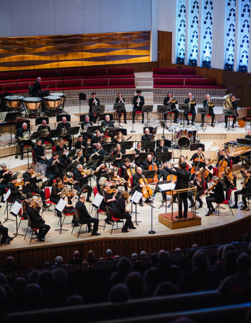 A photo of the Royal Liverpool Philharmonic Orchestra performing on stage, taken from above in the Grand Circle