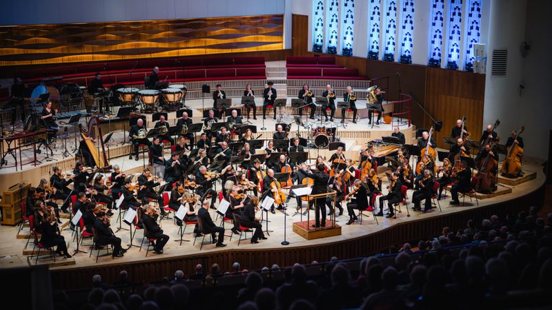 A photo of the Royal Liverpool Philharmonic Orchestra performing on stage, taken from above in the Grand Circle