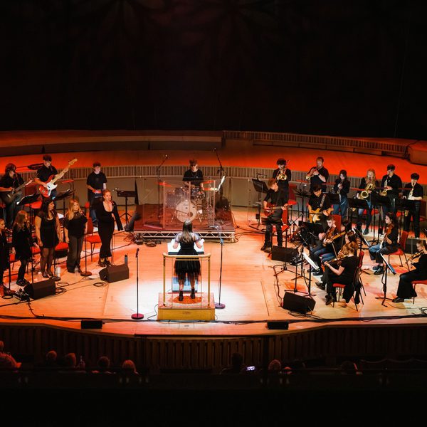 all members of the youth session band performing on stage with orange hue lighting