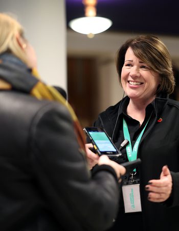 A female member of the Front Of House team greeting a member of the audience in the foyer