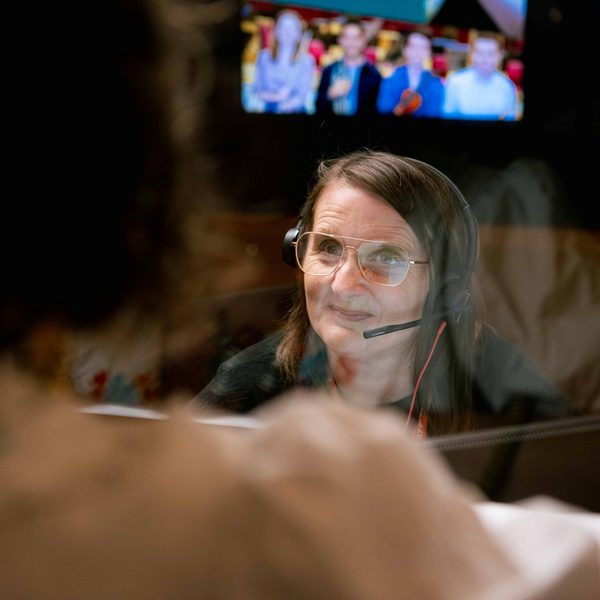 A white woman with short brown hair wearing an earpiece talking to a customer at Box Office