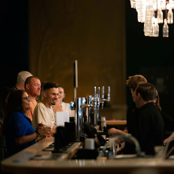 People waiting to be served at the bar with two servers dressed in black