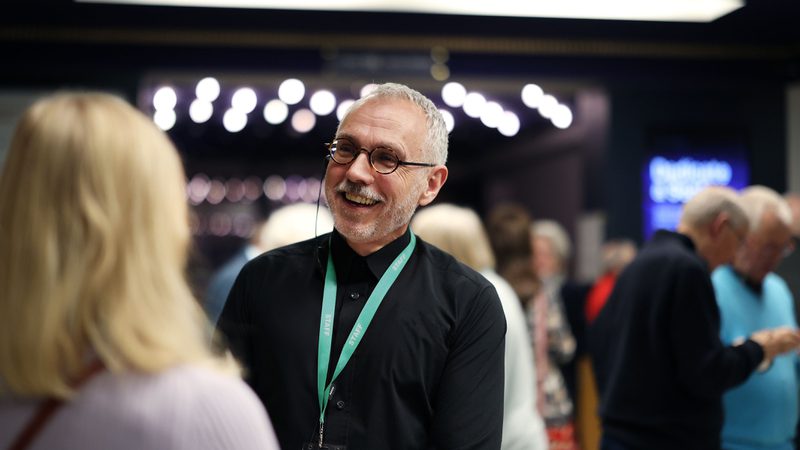 A male member of the Front of House team greeting an audience member in the foyer