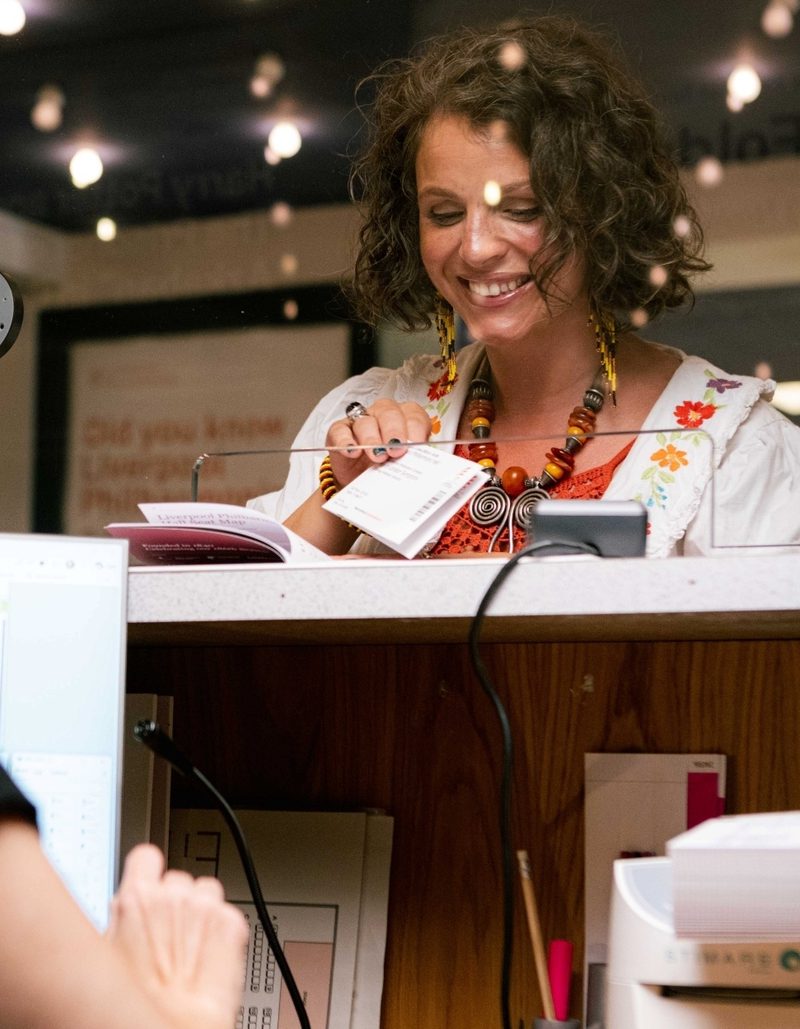 White woman with curly brown hair buying a ticket at Box Office