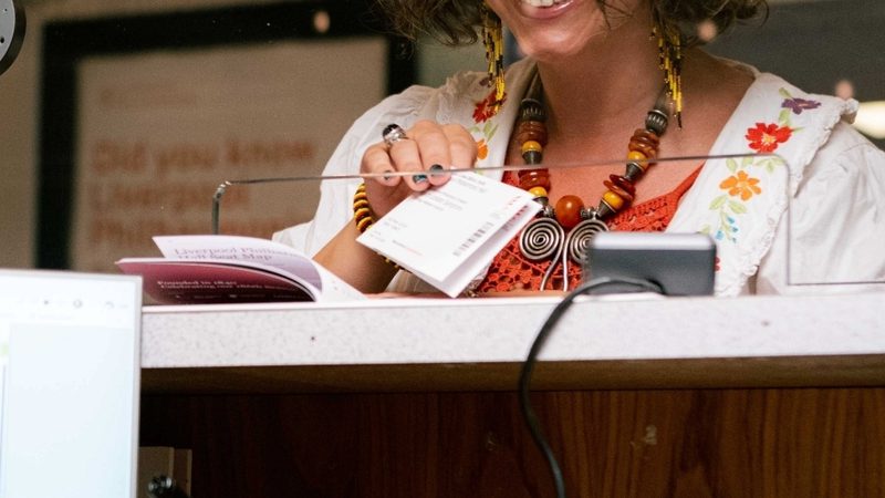 White woman with curly brown hair buying a ticket at Box Office