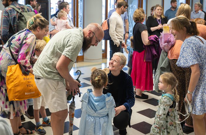 A family of 4 in the foyer, with young children dressed in costume, speaking to the conductor