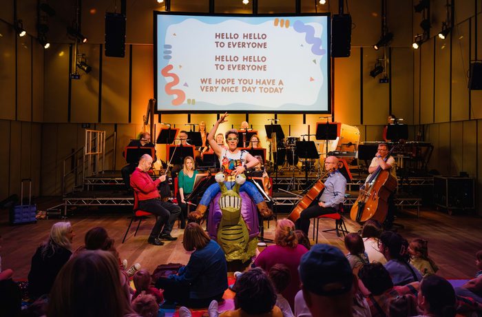 Claire Henry, dressed in an inflatable snail costume standing in front of a small orchestra
