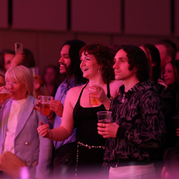 Two female and one male member of the audience standing and watching a concert in the Music Room