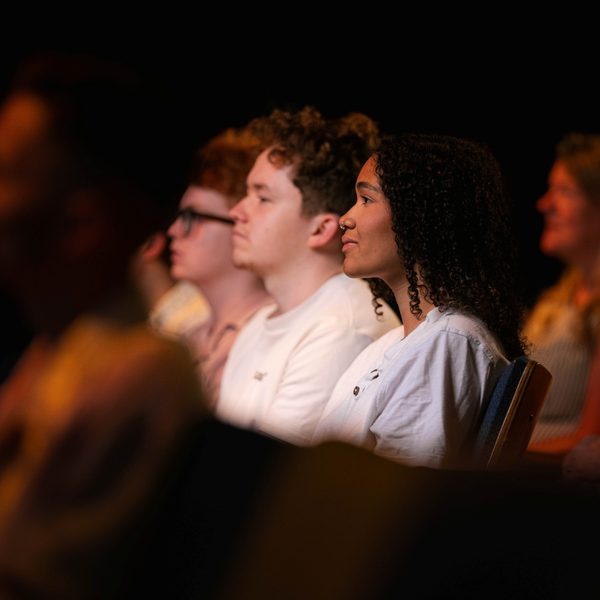 3 audience members sat in seats under spotlight