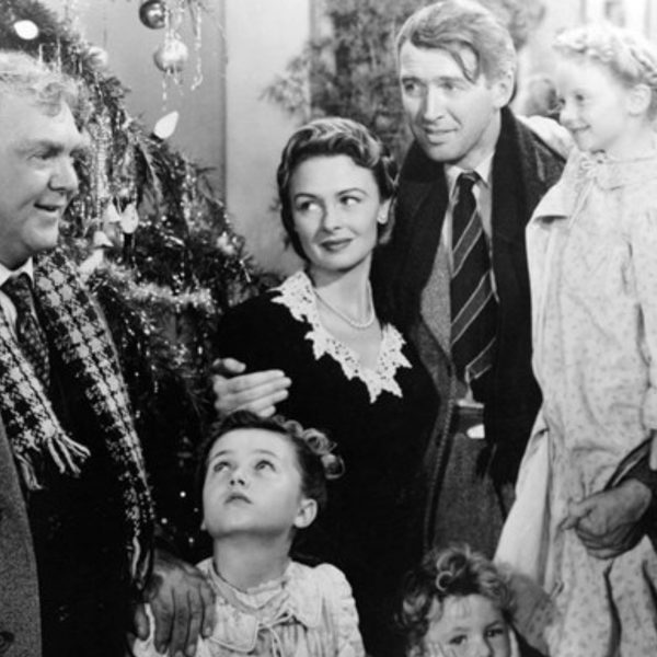 A family smartly dressed gathering in front of a Christmas tree.