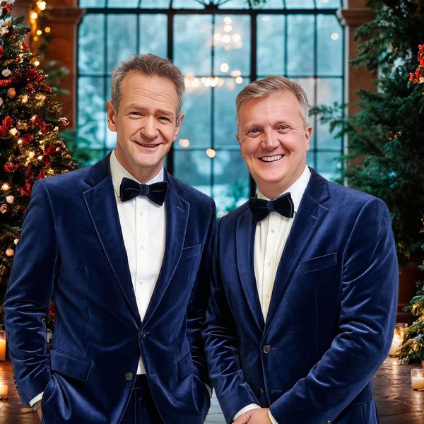 Aled Jones & Alexander Armstrong. Two white grey haired gentlemen in navy blue blazers and black bowties in a Christmas setting.