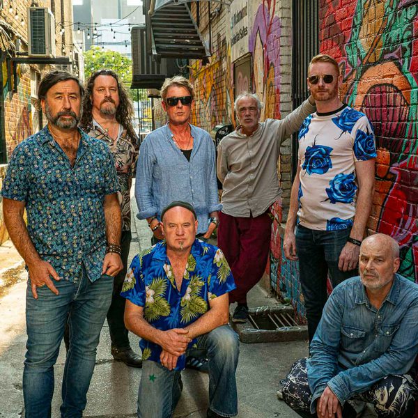 Members of Kíla standing and kneeling in an alleyway wearing blue patterned clothes