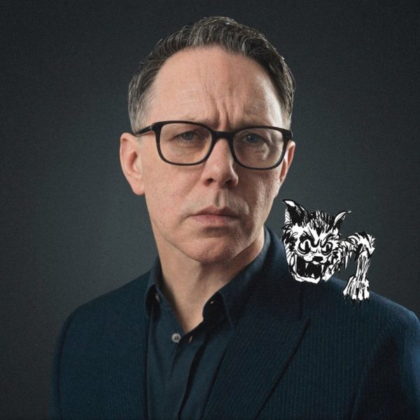 Reece Shearsmith looking into the camera pouting slightly with an illustrated creature on his shoulder