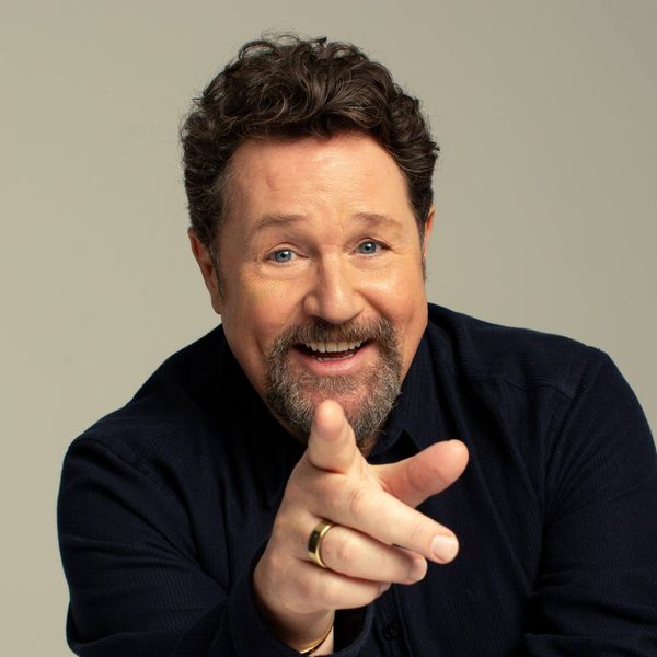 Michael Ball, a white man with short brown hair and a beard, pointing at the camera wearing a black shirt