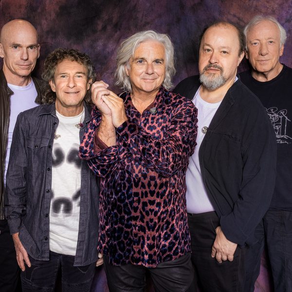 5 members of Marillion stood in a line smiling at the camera