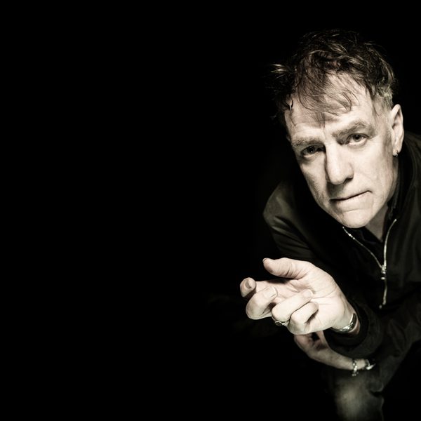 Black and white photo of white middle aged man leaning forward into the frame