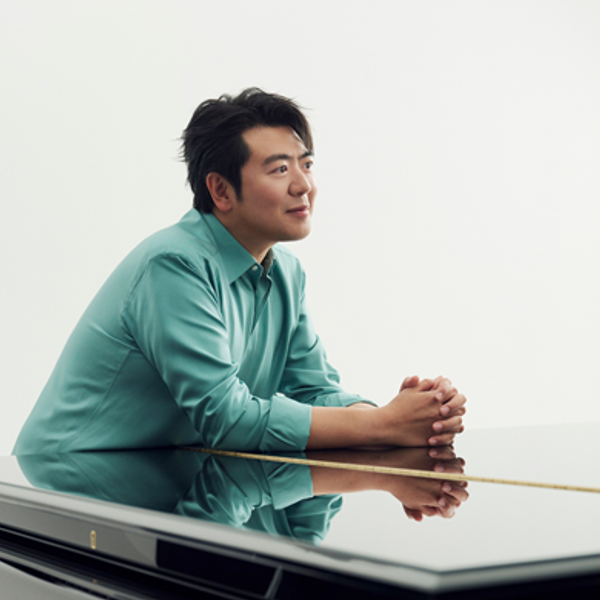 Lang Lang, an Asian man with short black hair wearing a blue shirt and leaning on a piano