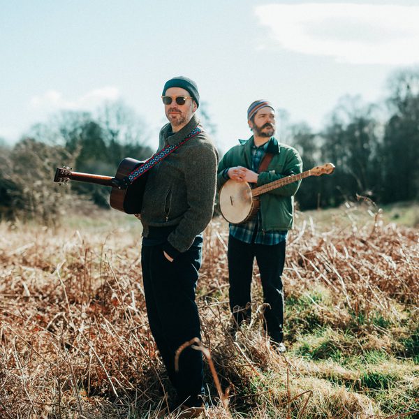 Kris Drever and Cahalen Morrison standing in a field holding their instruments