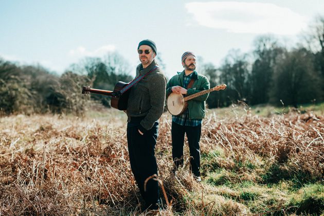 Kris Drever and Cahalen Morrison standing in a field holding their instruments