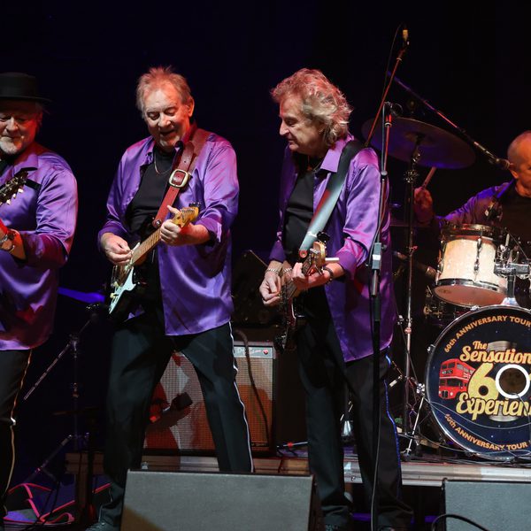 Four-man band wearing purple jackets and performing on stage
