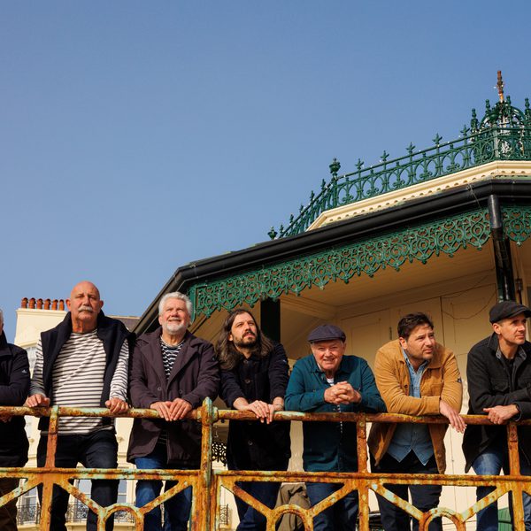 Members of Fisherman's Friends stood in a row on a pier looking forward