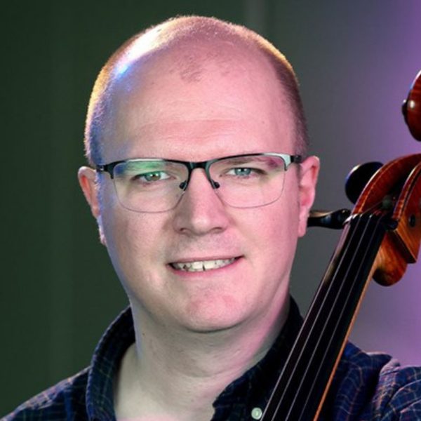 Mark Lindley, a white bald man with round glasses, holding his cello