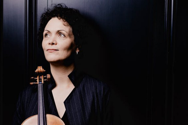 Tabea Zimmerman, a white woman with black curly hair, holding her viola and looking over to the left