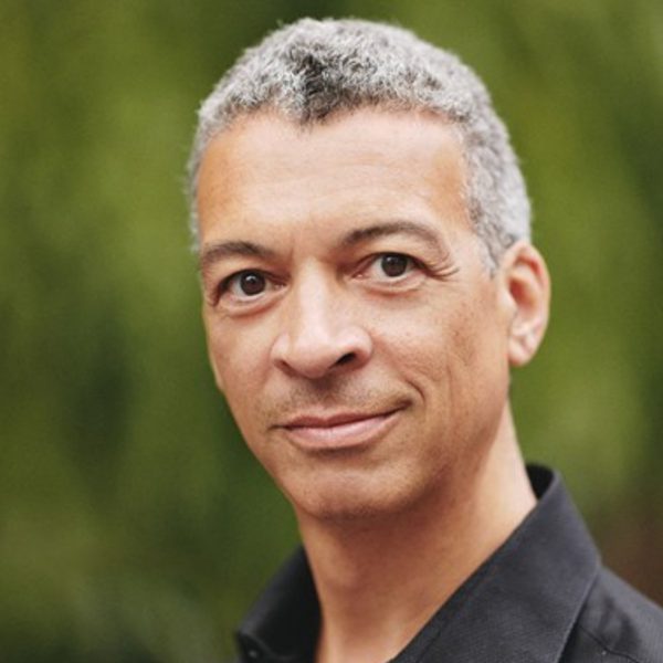 Roderick Williams, a mixed race man with short grey hair, wearing a black shirt and looking directly at the camera