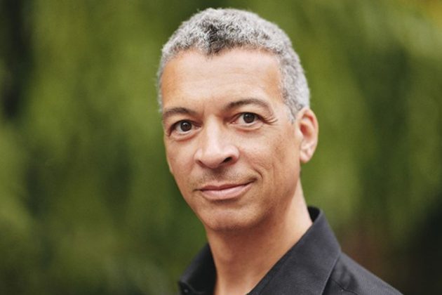Roderick Williams, a mixed race man with short grey hair, wearing a black shirt and looking directly at the camera