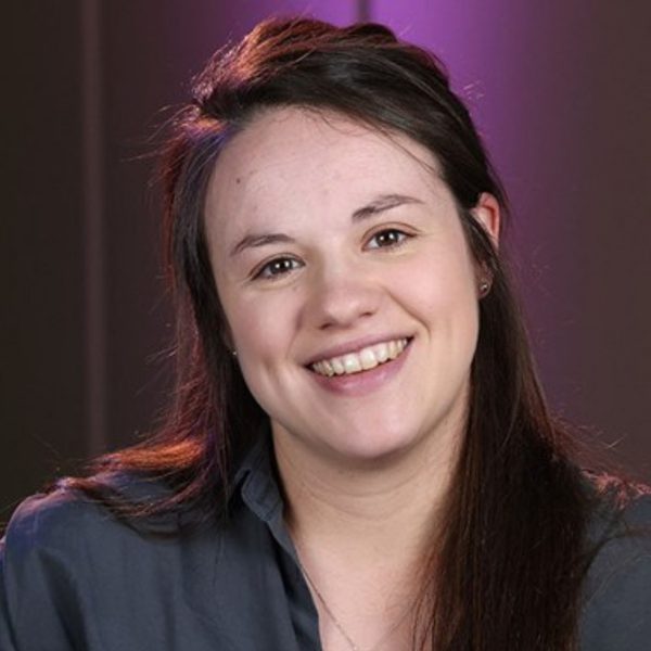 Rebecca Steventon, a white woman with long brown hair, wearing a dark blue shirt and smiling at the camera