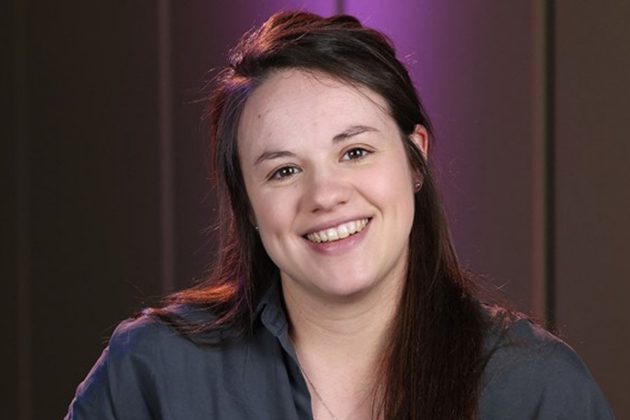 Rebecca Steventon, a white woman with long brown hair, wearing a dark blue shirt and smiling at the camera