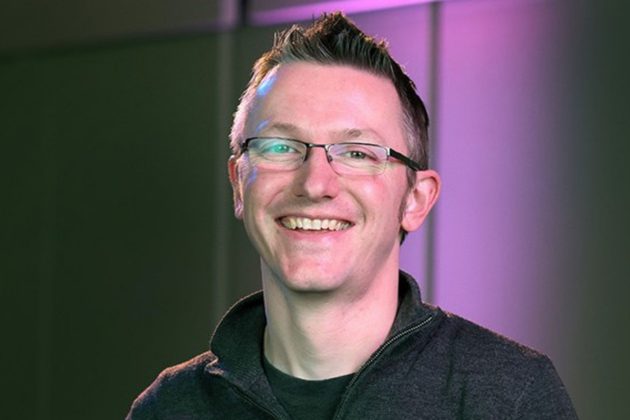 Ian Fair, a white man with short grey hair and square glasses, wearing a grey jumper