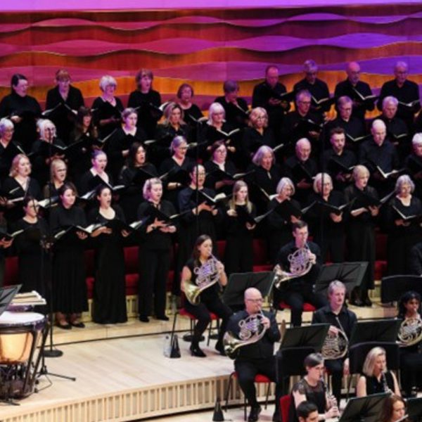 Members of the orchestra and choir performing on stage wearing all black